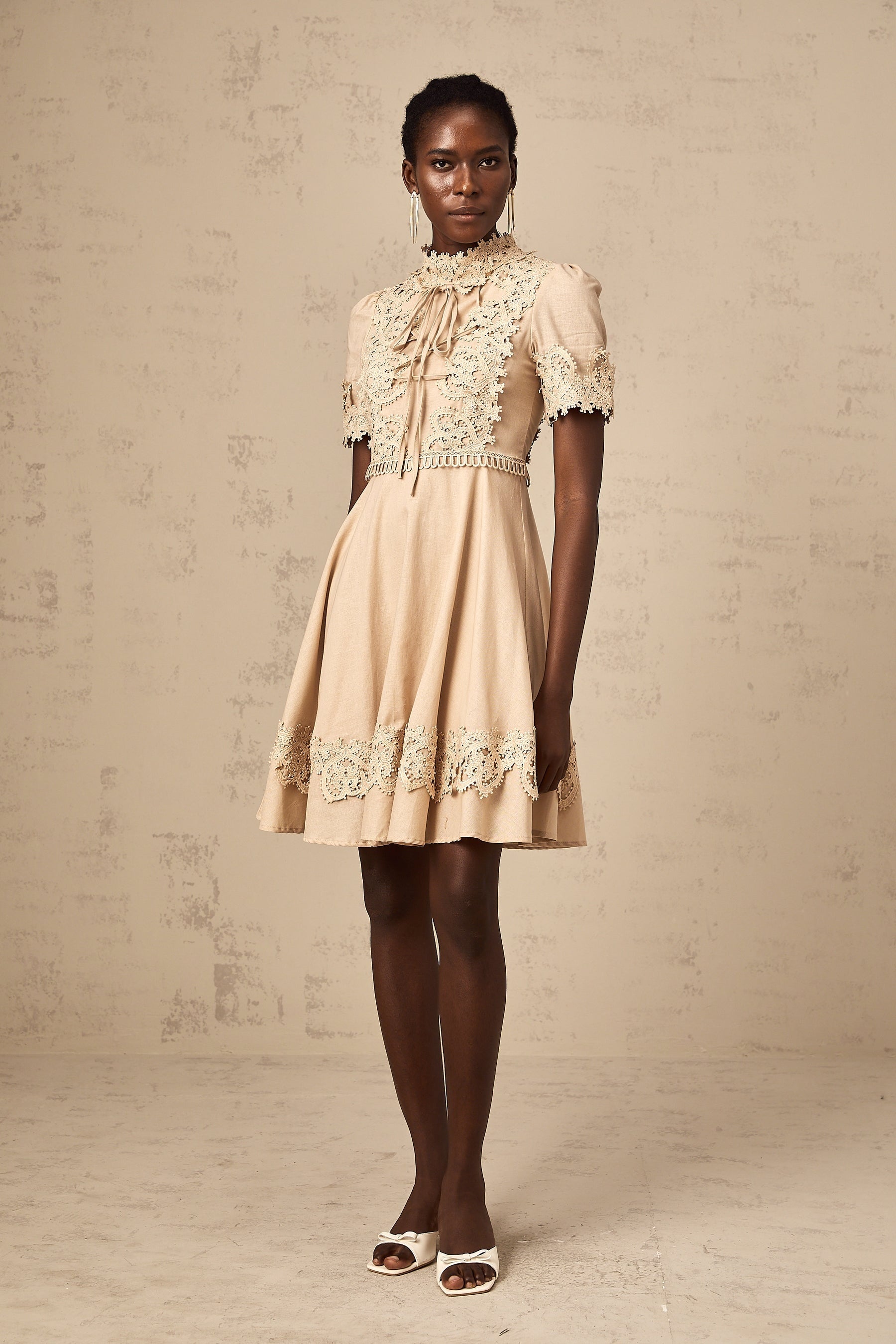 Young woman wearing a white flared mini dress with delicate corded lace pattern and short sleeves