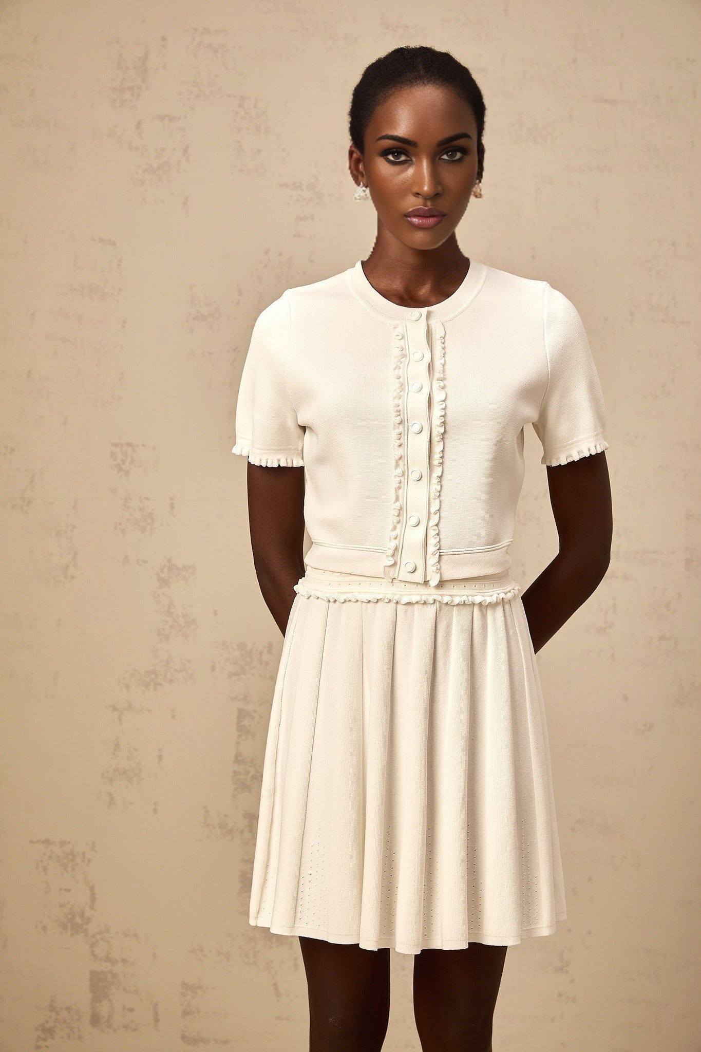 Young woman wearing a white knit top with ruffled trim and matching skirt Zelda style two piece outfit