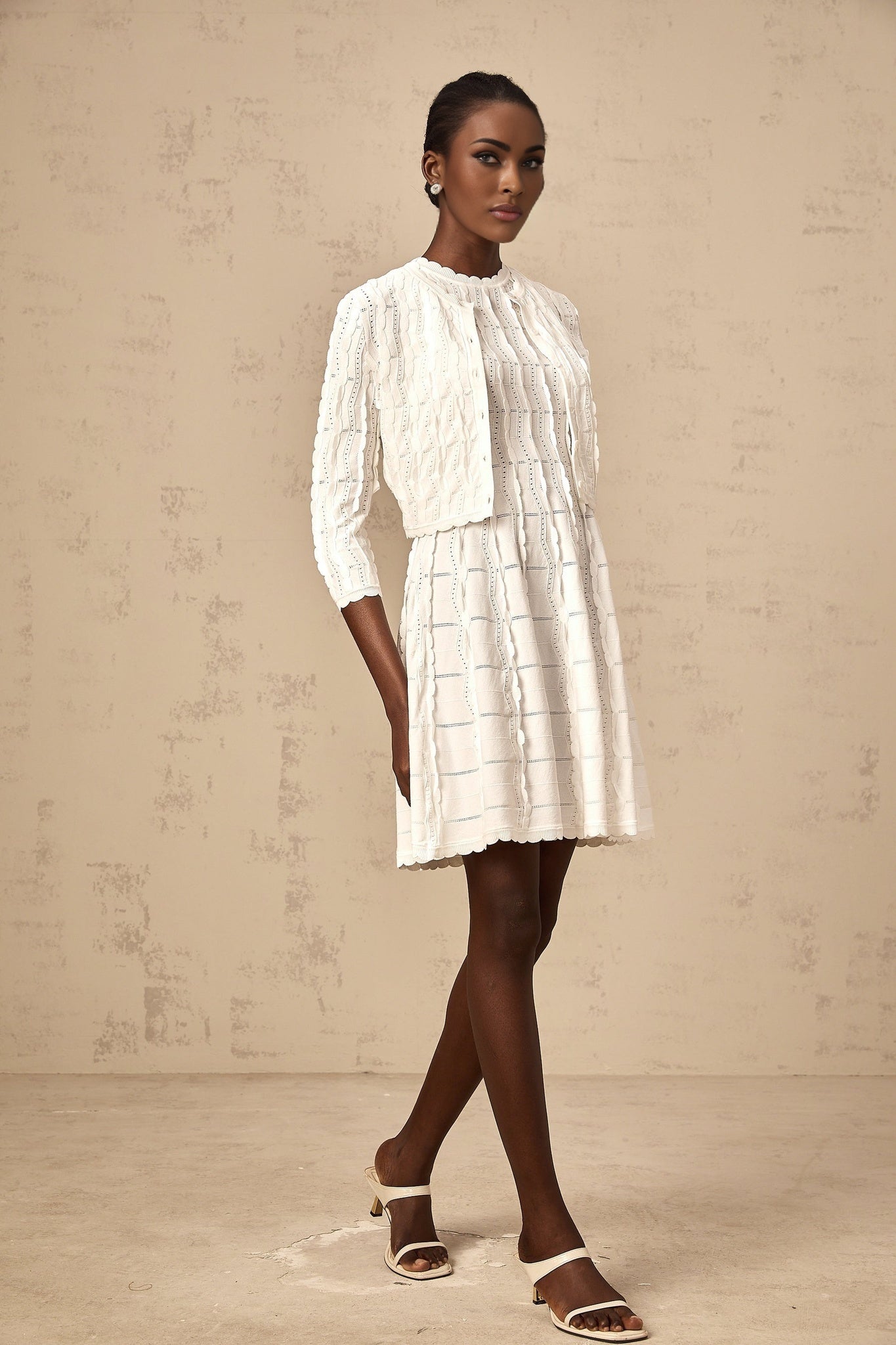 Young woman wearing a white knitted cardigan with ruffled details
