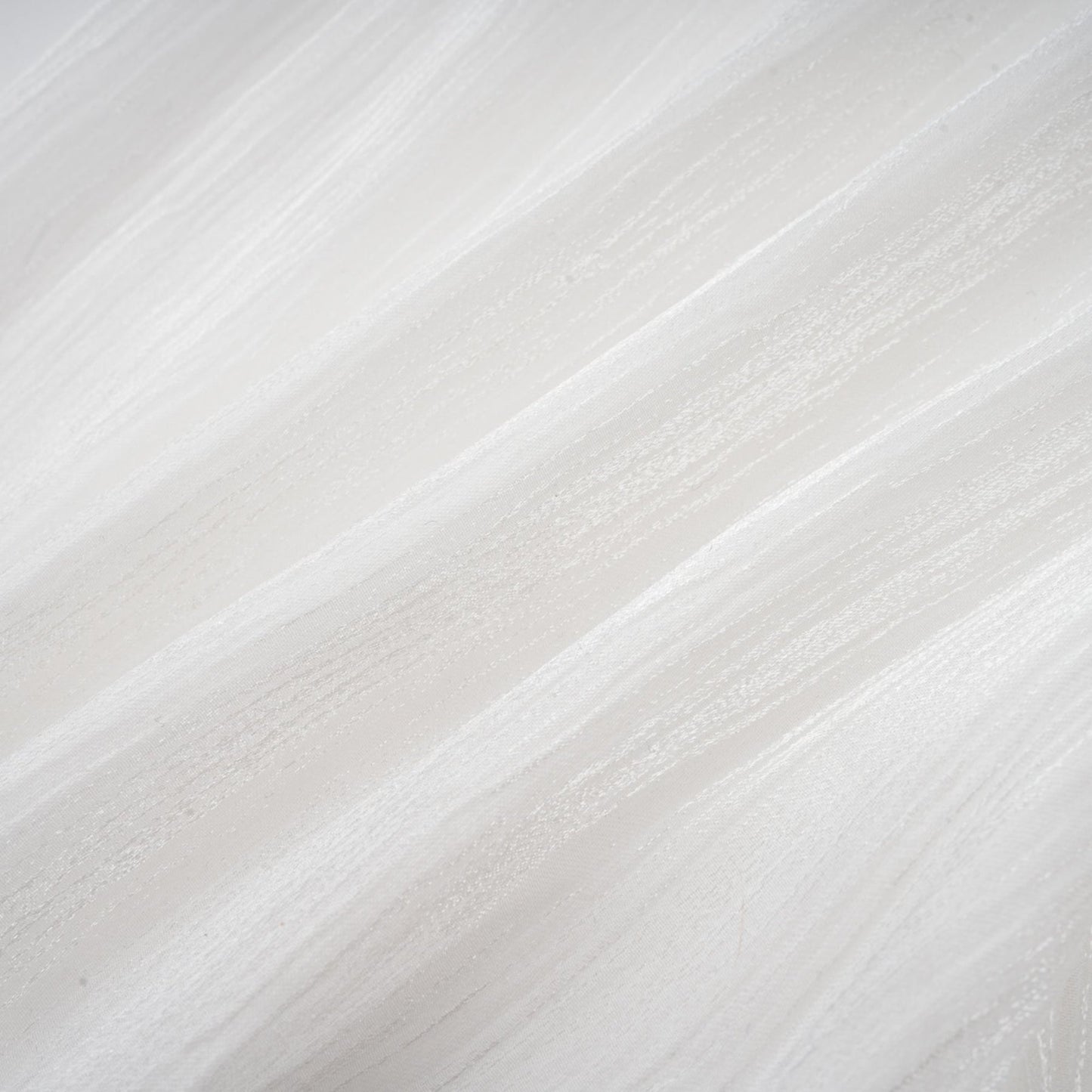 Young woman wearing a white mini dress with full pleats and cinched waist standing against plain background