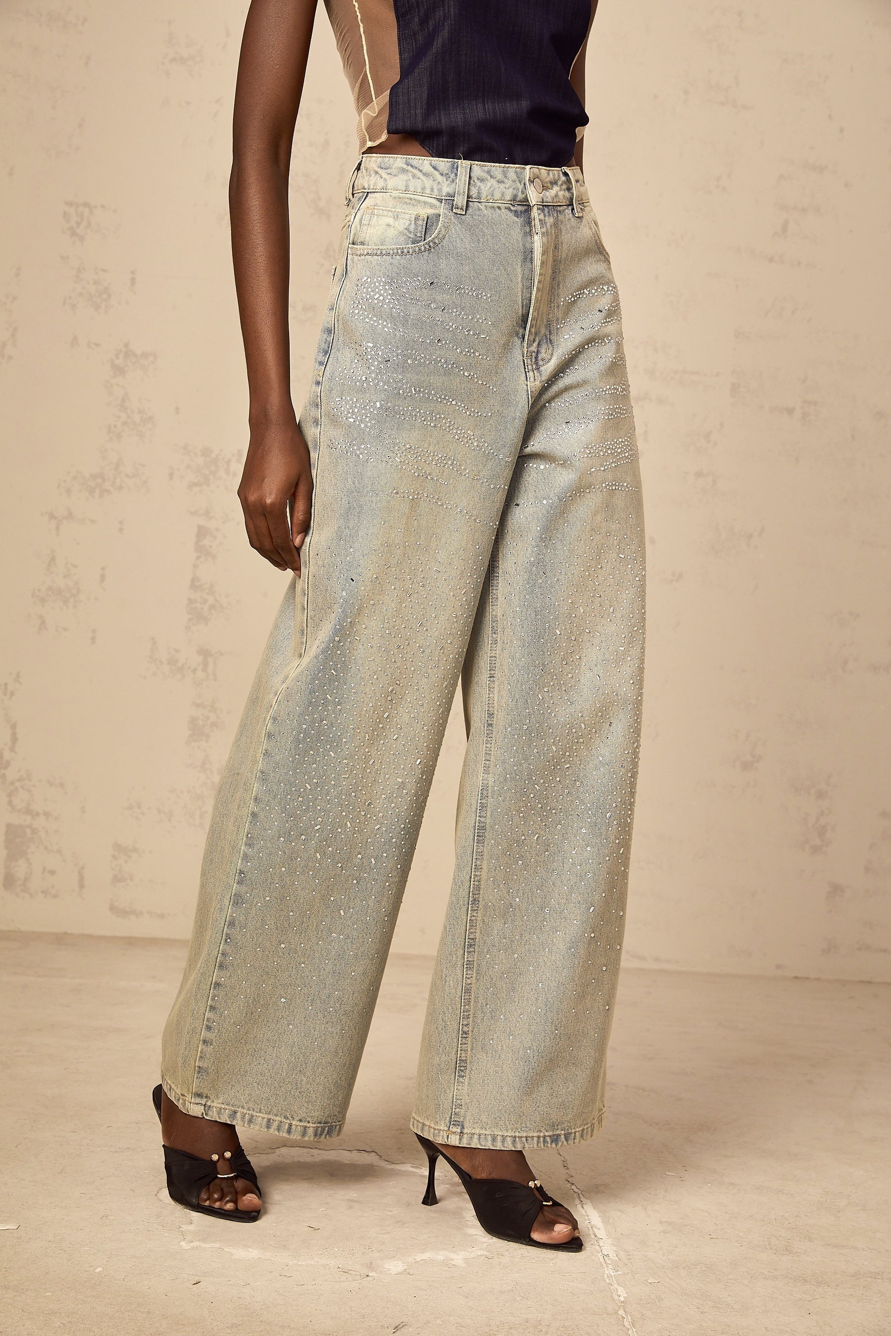 Young woman wearing light blue denim jeans embellished with rhinestones on the front pockets and along the sides