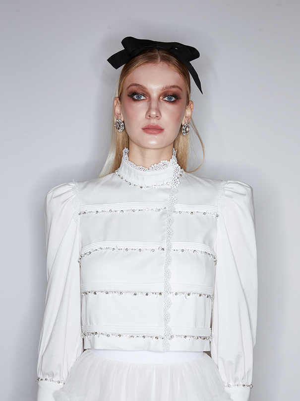 Sophia lace-embellished blouse with a high neckline, intricate lace detailing, puffed sleeves, and tailored fit, crafted from cotton, nylon, and spandex.