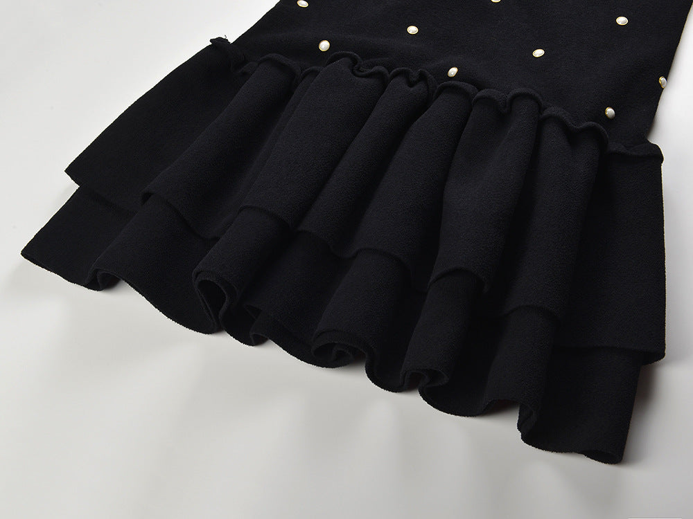 Sleeveless black mini dress featuring delicate pearl embellishments and a playful tiered ruffle skirt