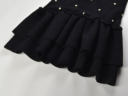 Sleeveless black mini dress featuring delicate pearl embellishments and a playful tiered ruffle skirt