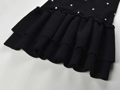 Sleeveless black mini dress featuring delicate pearl embellishments and a playful tiered ruffle skirt