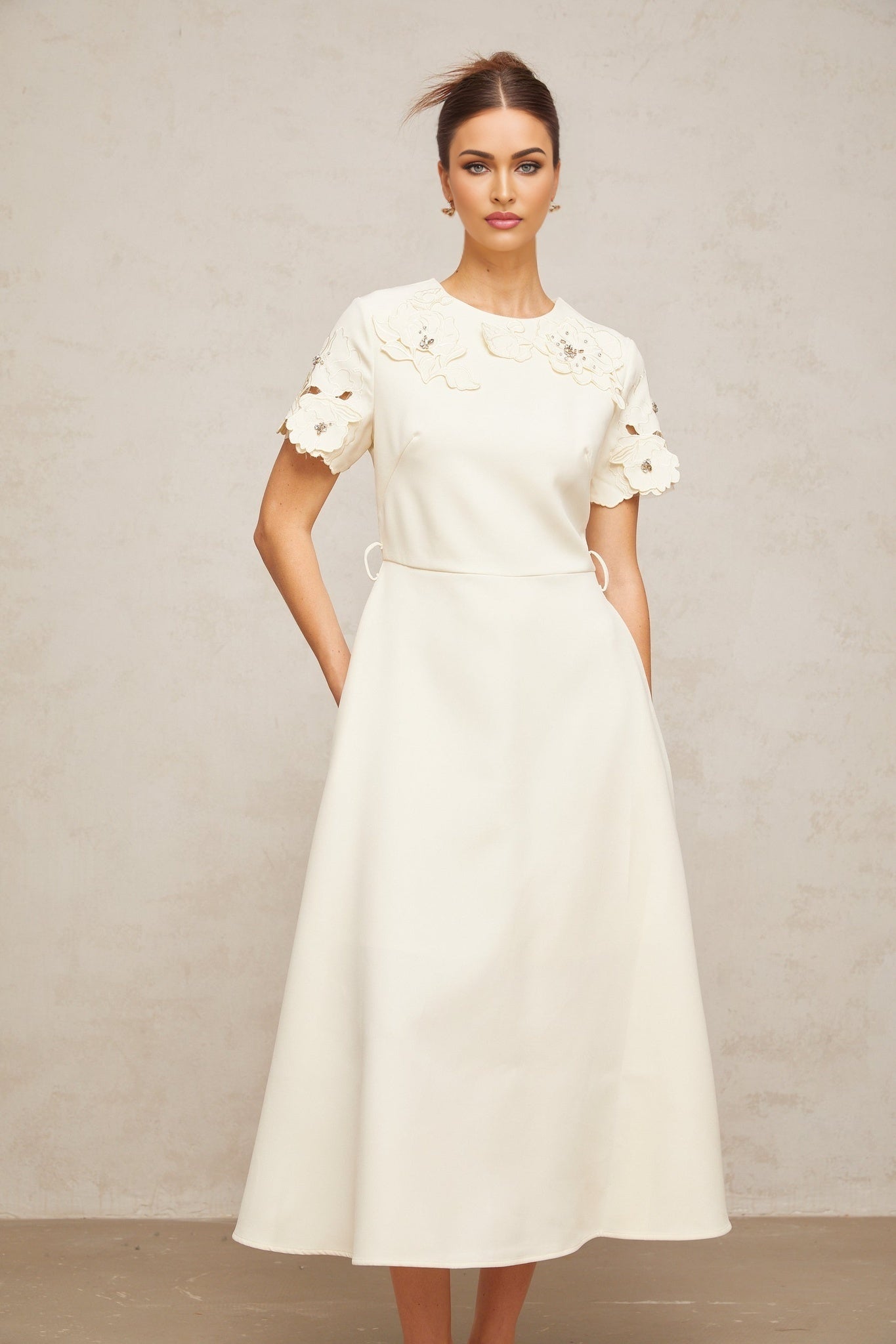 A beige midi dress with flared skirt featuring delicate floral appliques in neutral tones