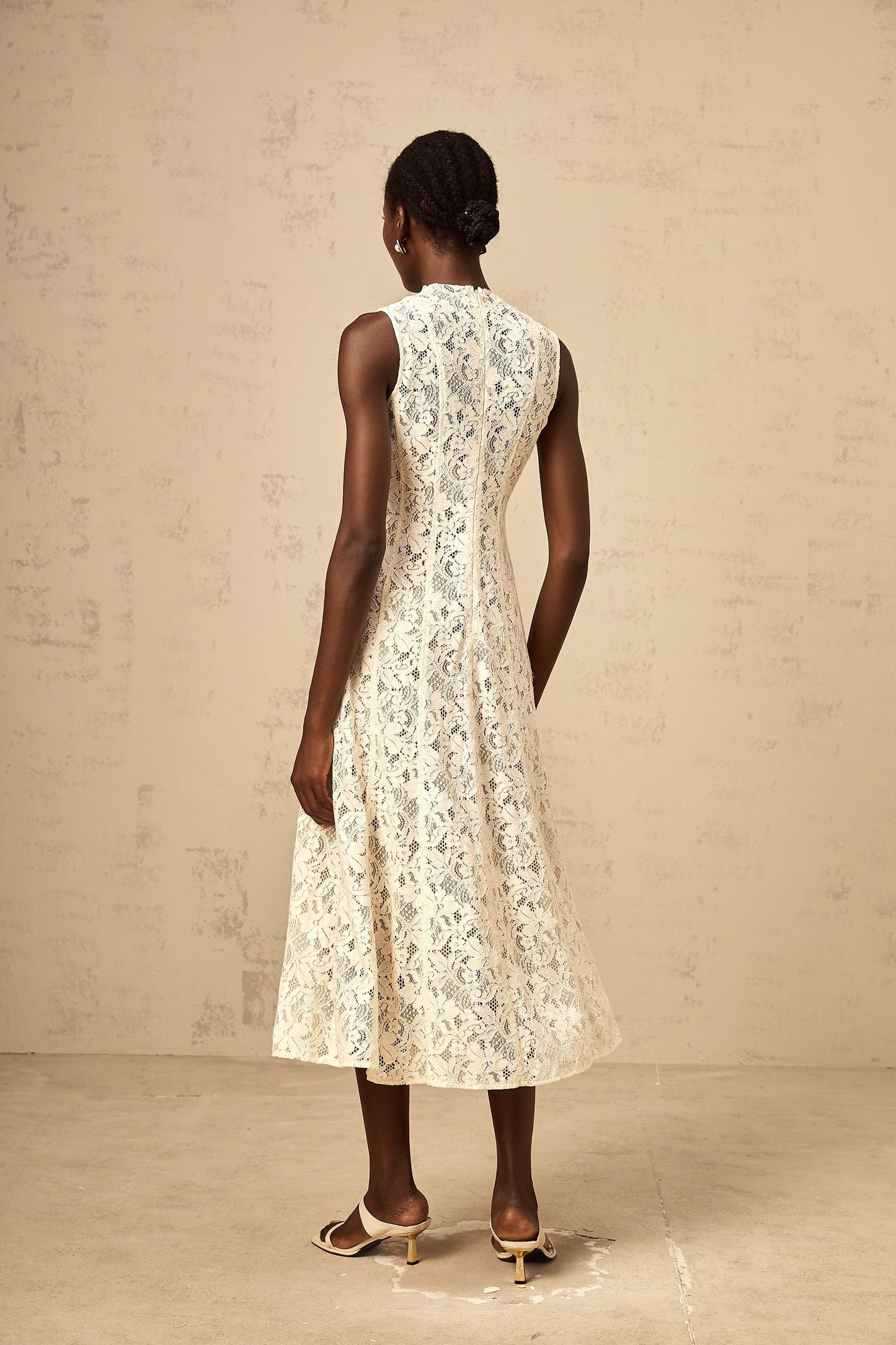 A beige midi dress with floral lace pattern and flared skirt design