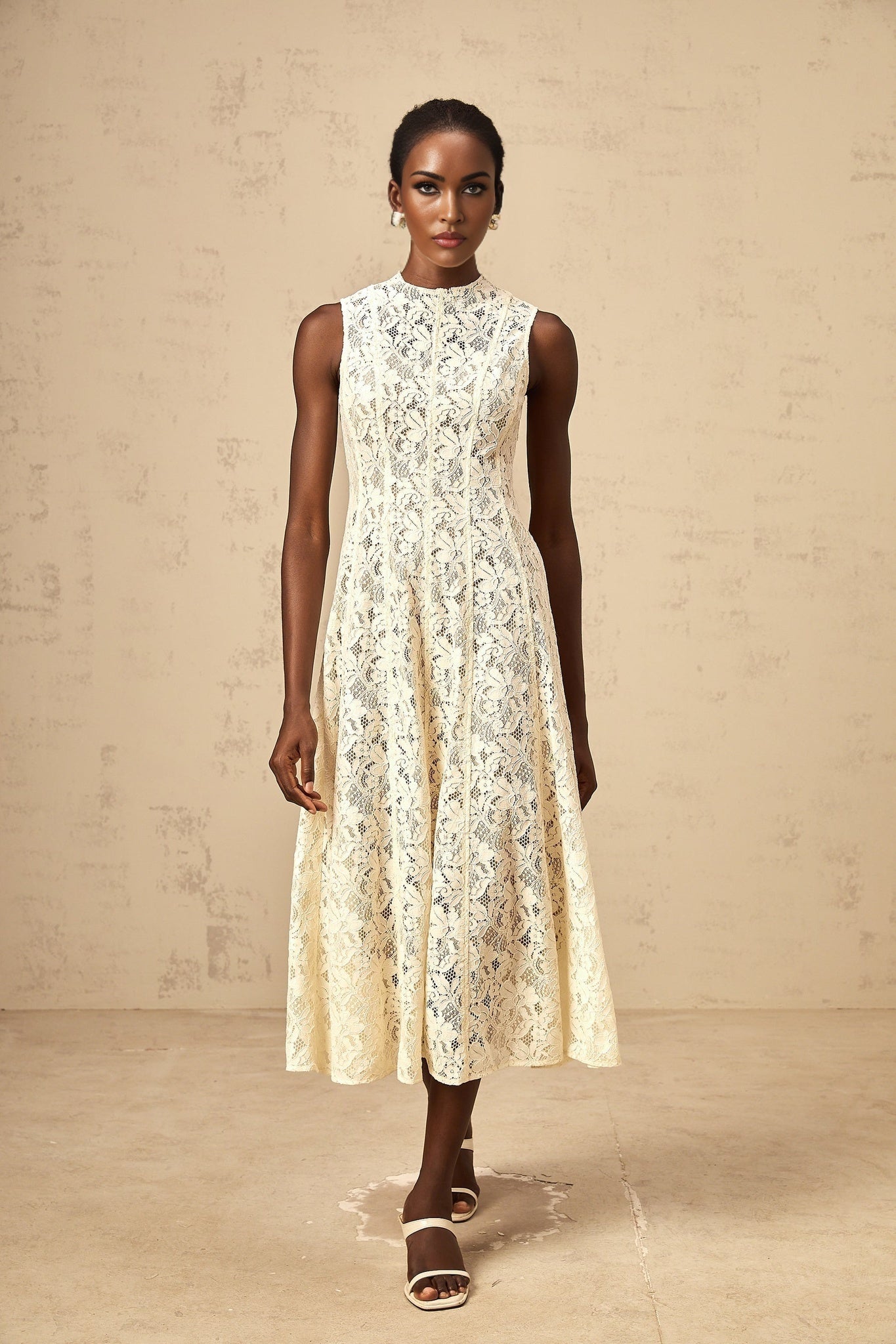 A beige midi dress with floral lace pattern and flared skirt on a white background