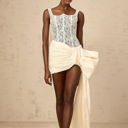 A beige mini dress with floral lace pattern featuring a bow accent and pencil skirt silhouette