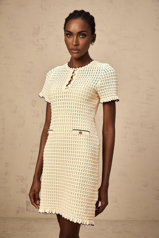 A beige mini dress with ruffled details and pointelle knit texture featuring a fitted bodice and short skirt