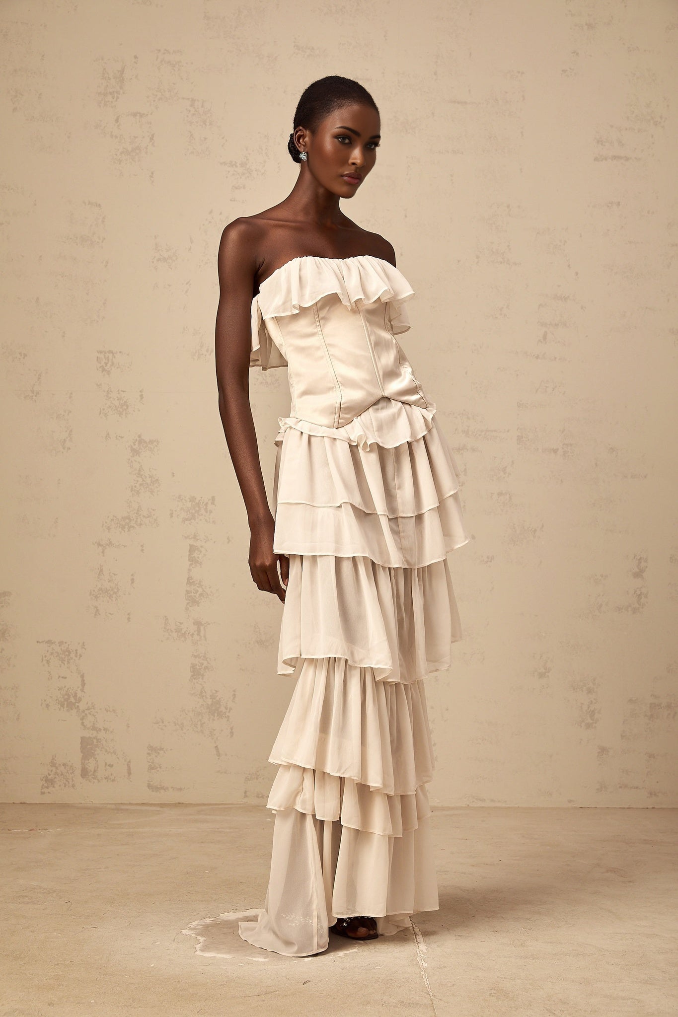 A beige offshoulder dress and corset set with tiered design featuring a matching top and skirt in a light neutral color