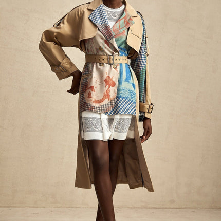 A beige trench coat with contrasting dark trim belted at the waist featuring a printed pattern and classic lapels