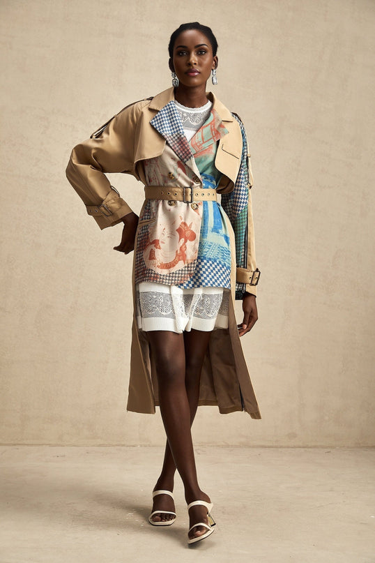 A beige trench coat with contrasting dark trim belted at the waist featuring a printed pattern and classic lapels
