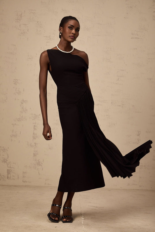 A black asymmetric midi dress with draped fabric details named Laurine featuring an uneven hemline and flowing silhouette