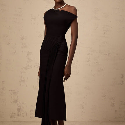 A black asymmetric midi dress with draped fabric details worn by a model standing against a plain background