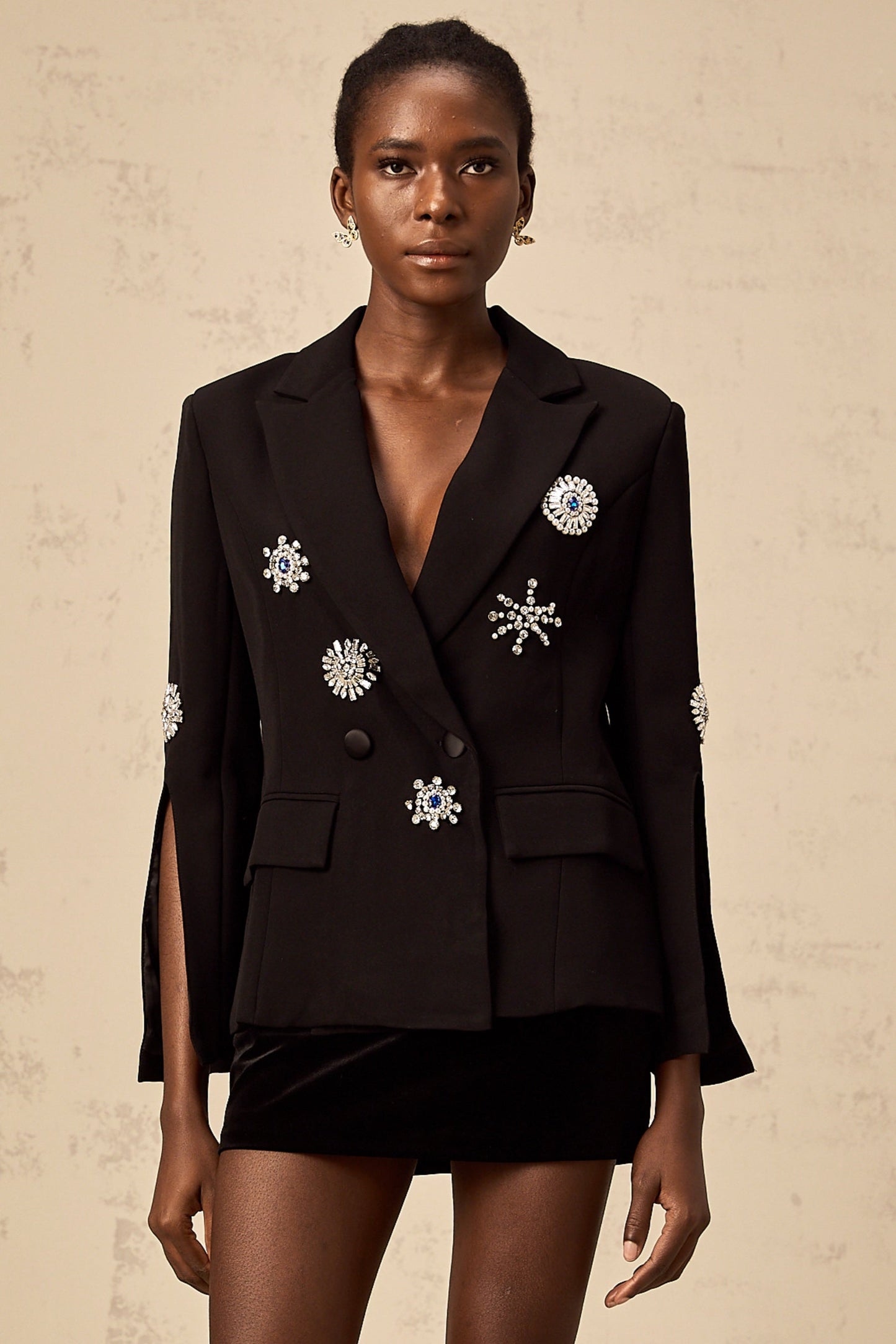 A black blazer with crystal embellishments and slit cuffs featuring a sleek design and sparkly accents