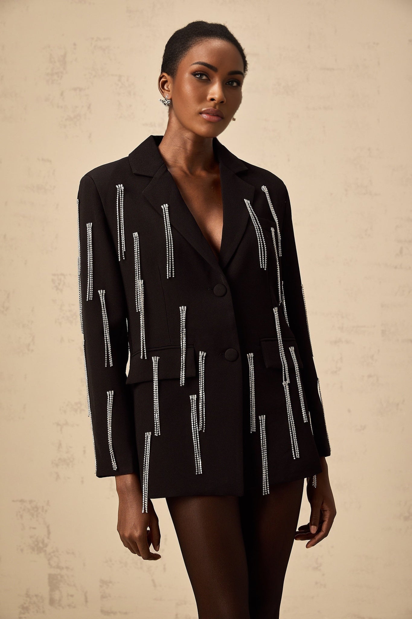 A black blazer with crystal tassels adorning the garment providing a sparkly and glamorous accent to the classic silhouette