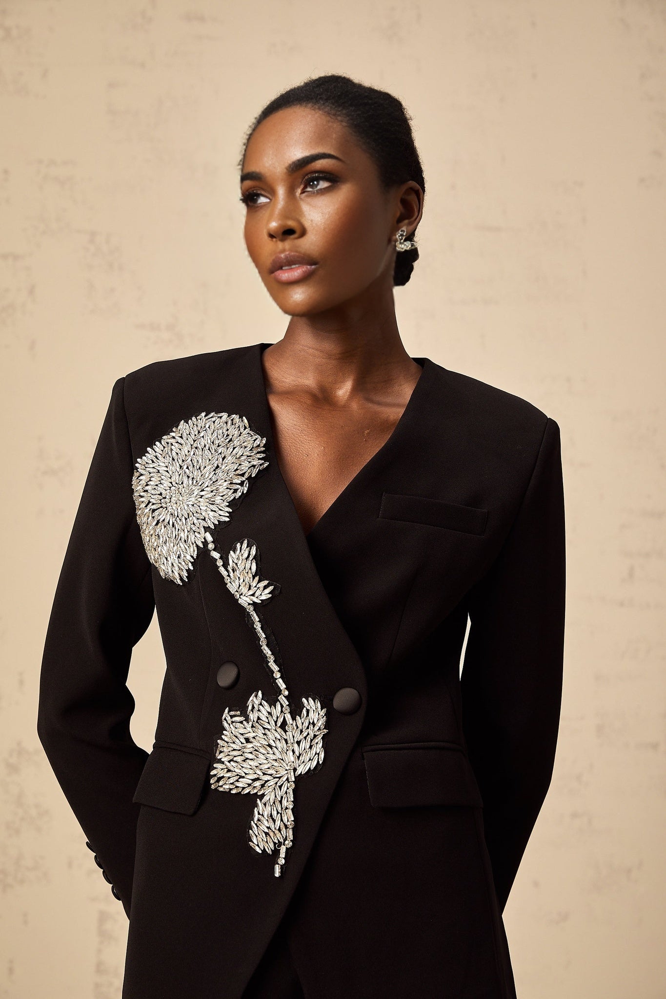 A black blazer with floral embellishments featuring a pattern of small flowers decorating the fabric