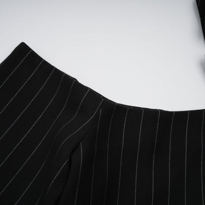 A black blazer with white stripes featuring an open back design worn by a model