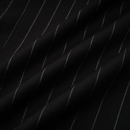 A black blazer with white stripes featuring an open back design worn by a model