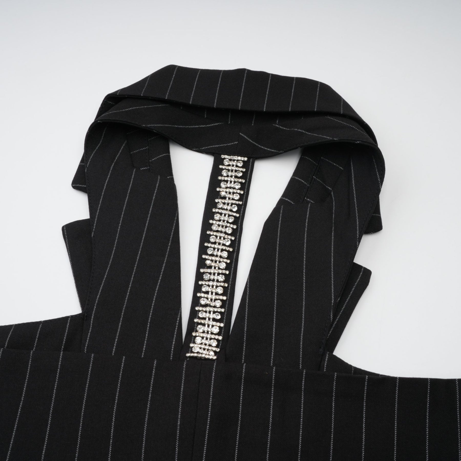 A black blazer with white stripes featuring an open back design worn by a model