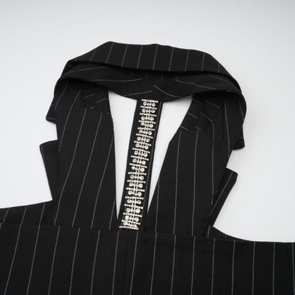 A black blazer with white stripes featuring an open back design worn by a model