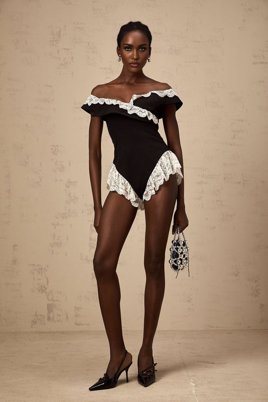 A black bodysuit with delicate lace trim details worn by a female model