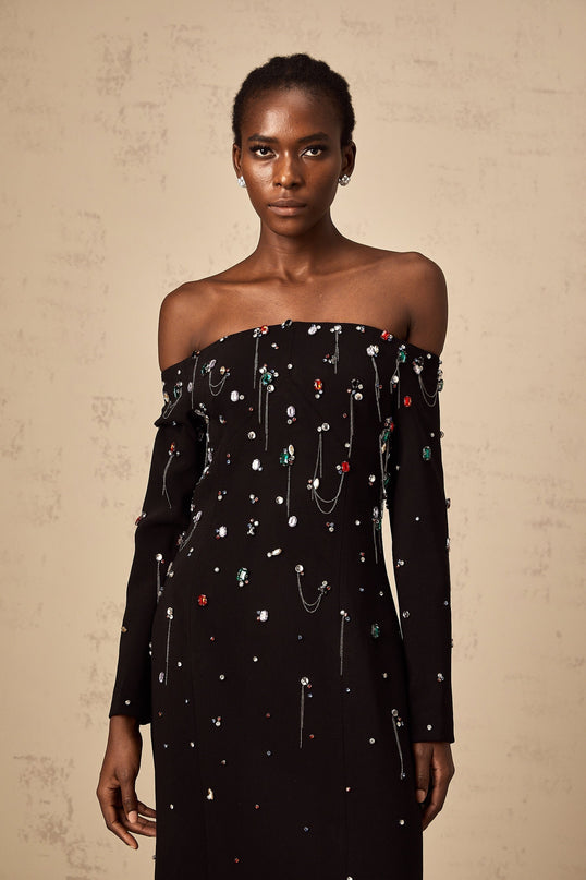 A black crystal embellished offshoulder maxi dress on a mannequin or model showcasing the Gabrielle design with a floorlength silhouette and elegant neckline
