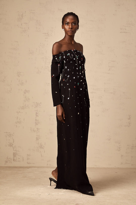 A black crystalembellished offshoulder maxi dress on a mannequin against a plain background