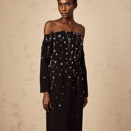 A black crystalembellished offshoulder maxi dress on a mannequin or model showcasing the elegant and formal design of the Gabrielle dress