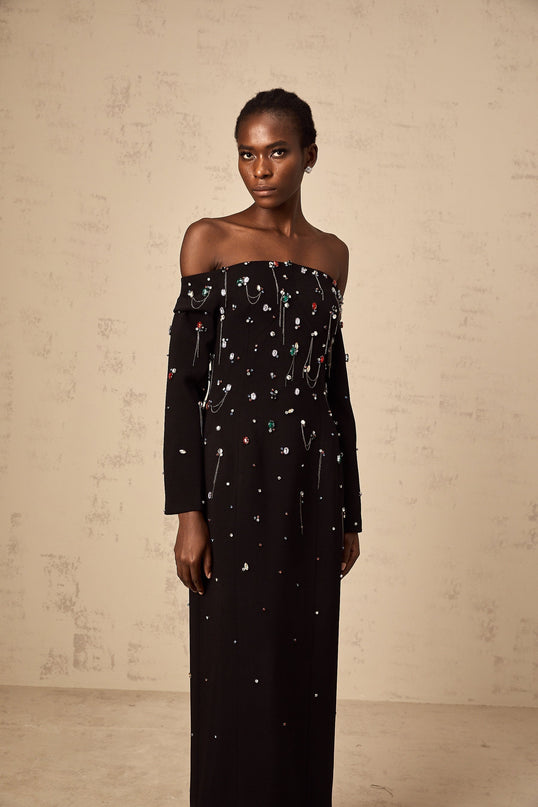 A black crystalembellished offshoulder maxi dress on a mannequin or model showcasing the elegant and formal design of the Gabrielle dress