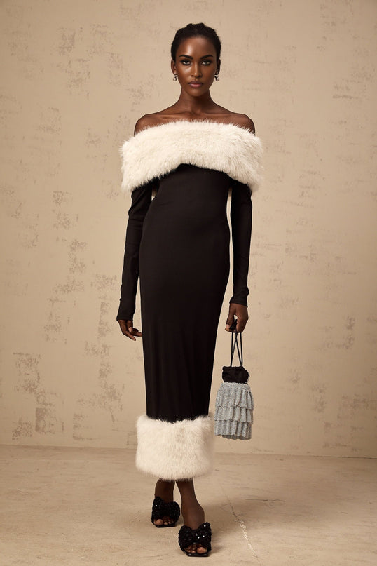 A black faux fur midi dress with an offshoulder neckline worn by a model standing against a plain background