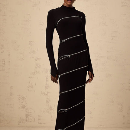 A black fitted maxi dress with zipper details worn by a model standing against a plain background