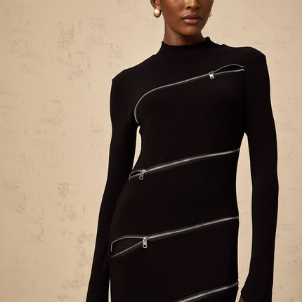 A black fitted maxi dress with zipper details worn by a model standing against a plain background