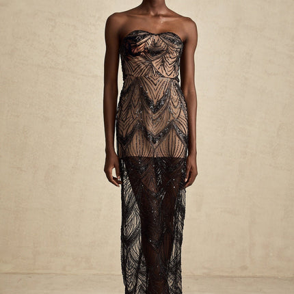 A black floor length dress with a corset bodice covered in shimmering sequins and a flowing mesh skirt