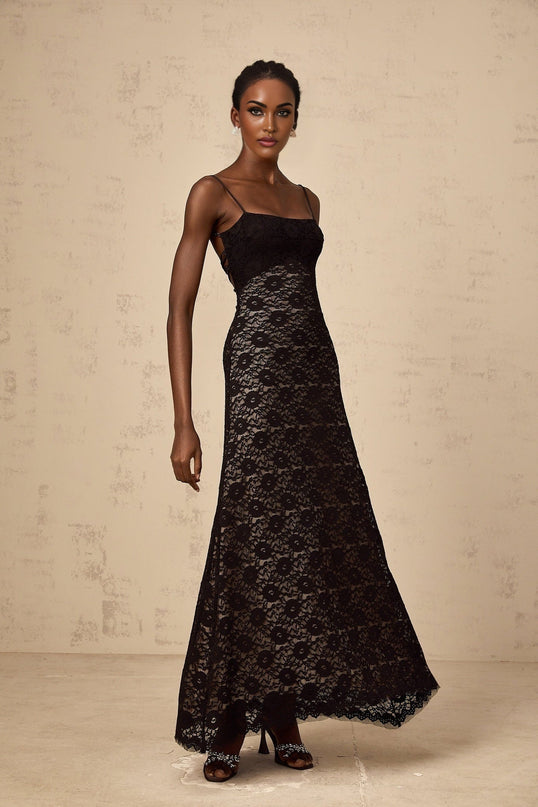A black floor length maxi dress with an open back design and intricate floral lace detailing throughout the garment