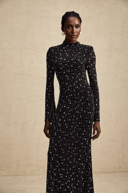 A black floor length maxi dress with sheer fabric and embellished details worn by a model