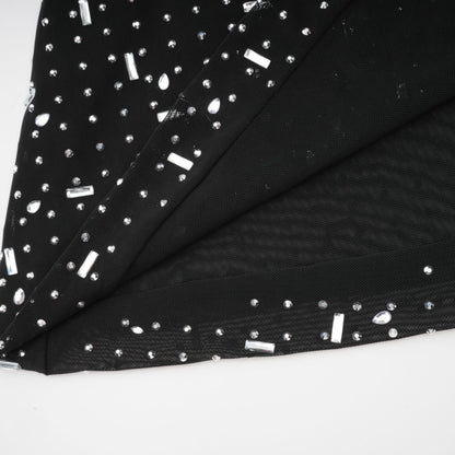 A black floor length maxi dress with sheer fabric and embellished details worn by a model