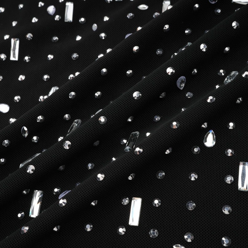 A black floor length maxi dress with sheer fabric and embellished details worn by a model