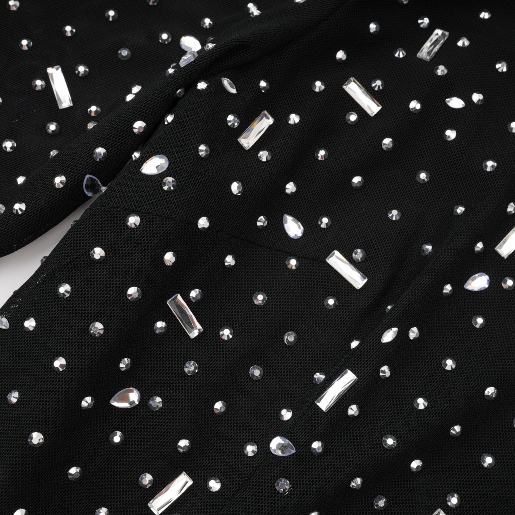A black floor length maxi dress with sheer panels and embellished details worn by a model against a plain background