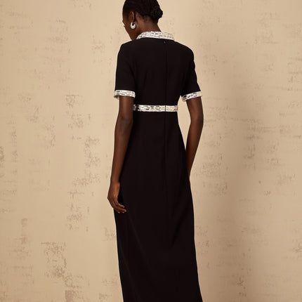 A black floorlength maxi dress with a front slit and crystal embellishments worn by a model standing against a plain background