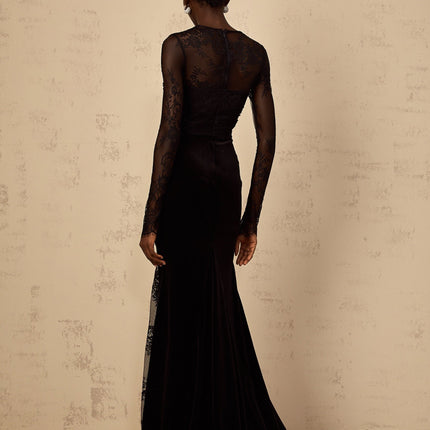 A black floorlength mermaid style dress with floral lace detailing named Ursula shown on a model against a plain background