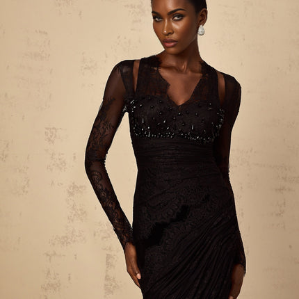 A black floorlength mermaid style dress with floral lace pattern worn by a model standing in a neutral background