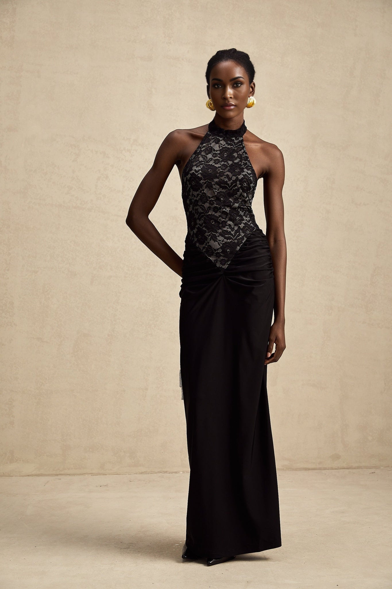 A black floral lace maxi dress with halter neckline named Camille featuring a long flowing skirt and intricate lace pattern throughout