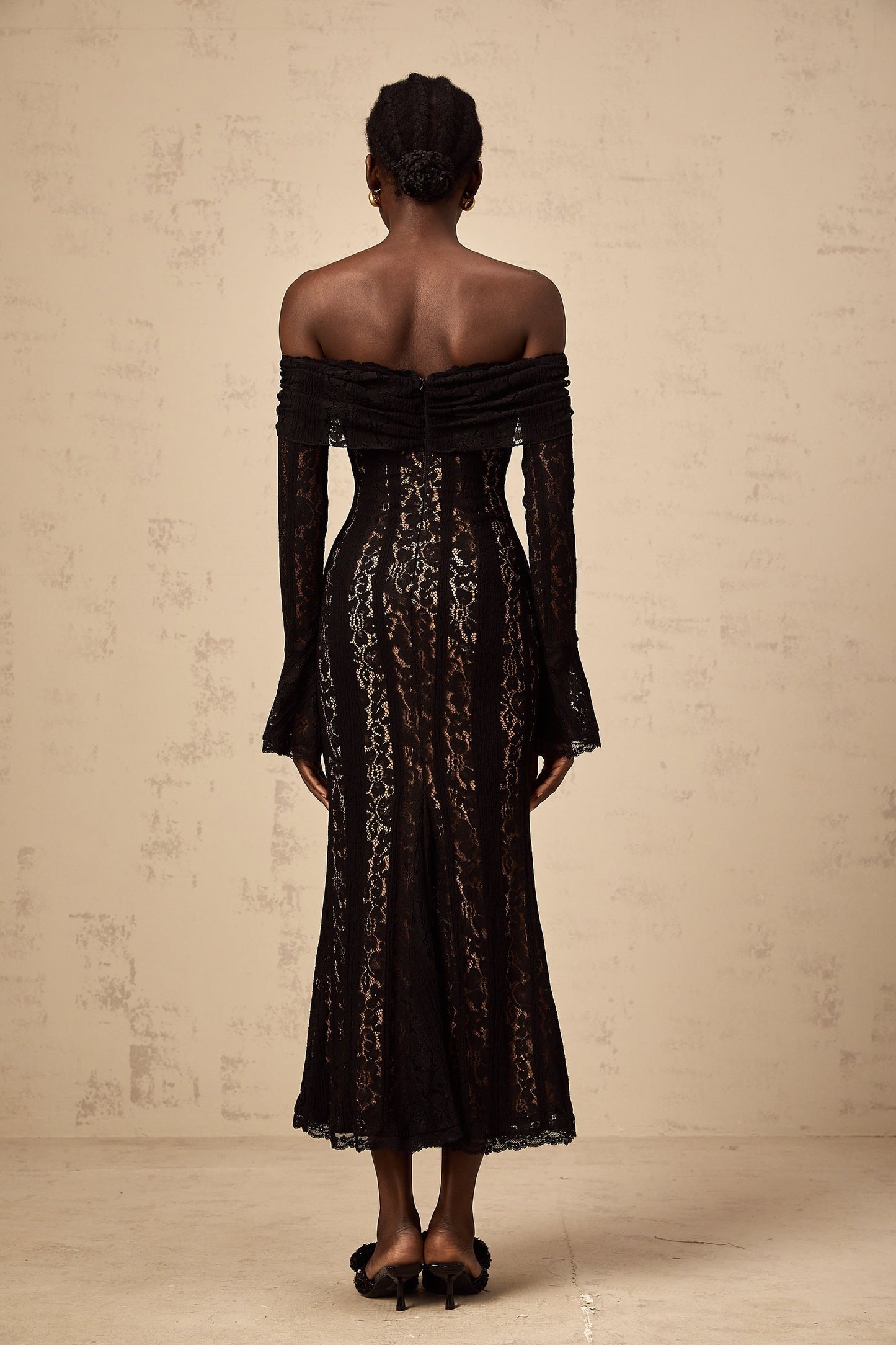 A black floral lace midi dress with flared cuffs named Emeline featuring an intricate floral pattern and a feminine silhouette