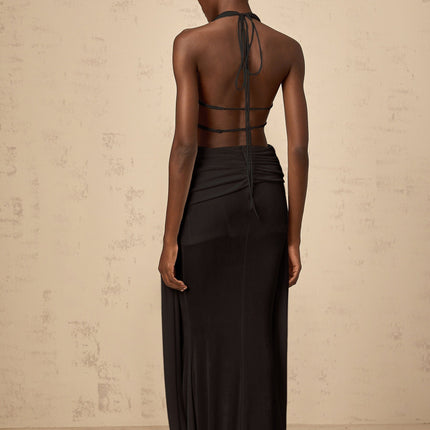 A black halterneck maxi dress with a backless design featuring a long flowing skirt and sleek silhouette