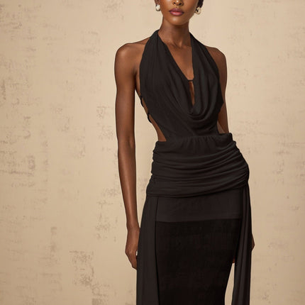A black halterneck maxi dress with a backless design hanging on display