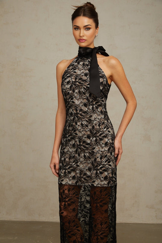 A black halterneck maxi dress with floral lace detailing named Coralie shown on a model against a plain background