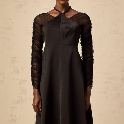 A black halterneck midi dress with panel detailing worn by a model against a plain background