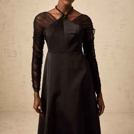 A black halterneck midi dress with panel details worn by a model against a plain background